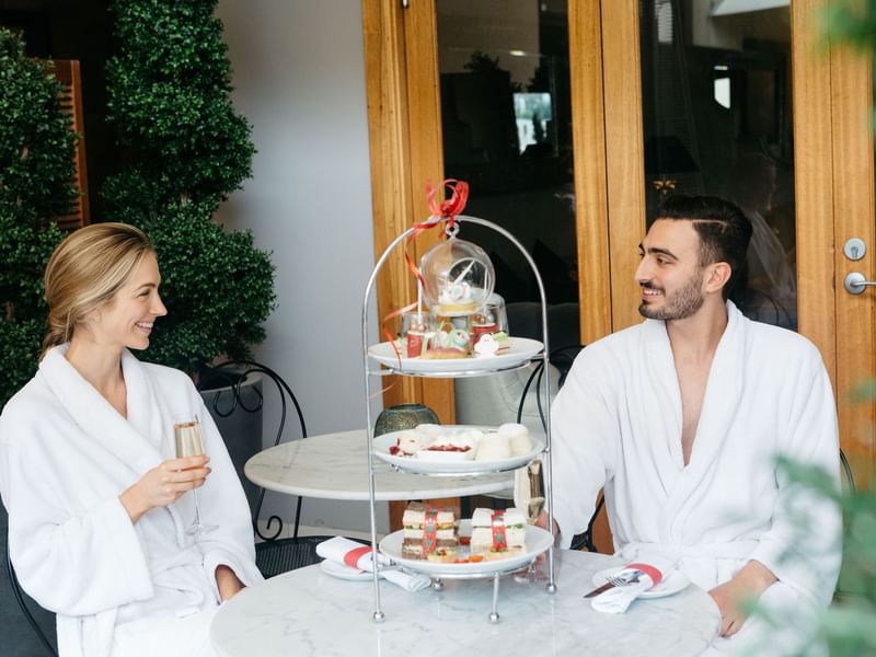 Couple in robes with a tiered tray of desserts at Stephanies Luxury Spa near Sofitel Brisbane Central