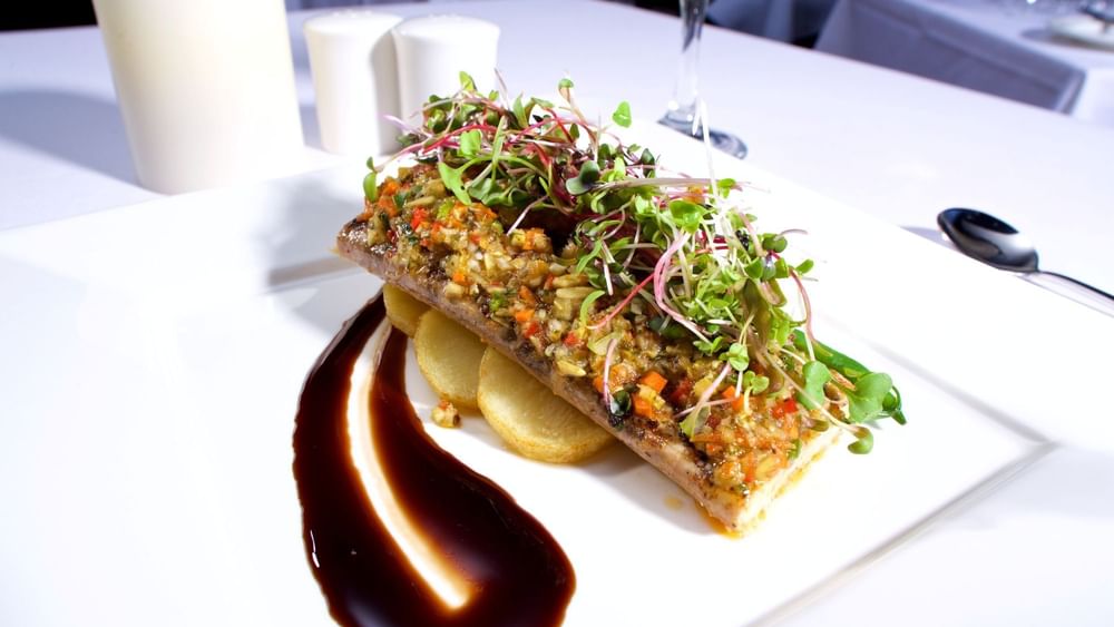 Seasoned fish fillet with roasted potatoes under fresh microgreens in Abbiocco at Warwick Paradise Island Bahamas