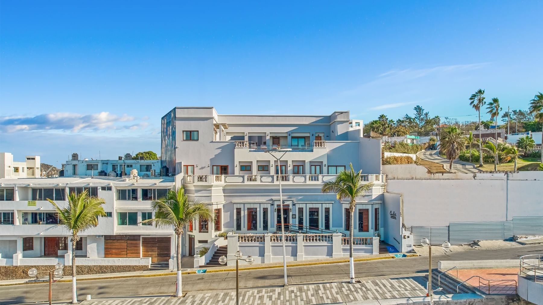 Exterior view of a Curamoria Collection, featuring multiple levels, balconies, and palm trees