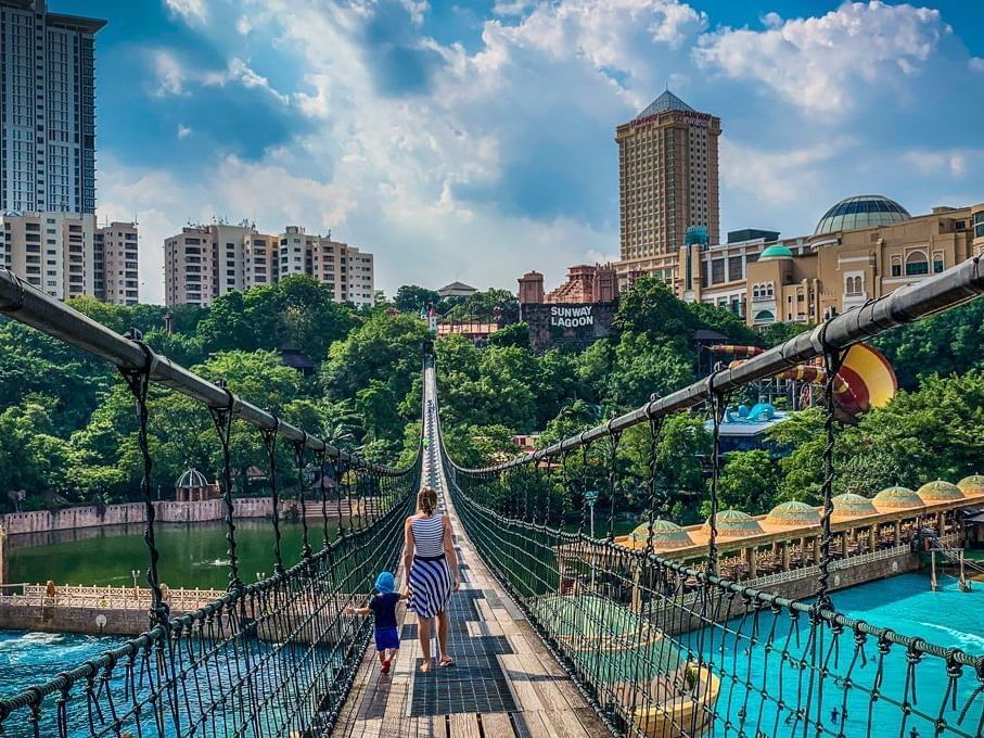 Mother & son walking on a suspension bridge, surrounded by lush greenery near Saujana Hotel Kuala Lumpur