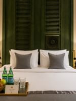 Fresh fruit basket with bottled water on bed before dark paneled headboard in Accessible Room at Naviti by Warwick Jeddah