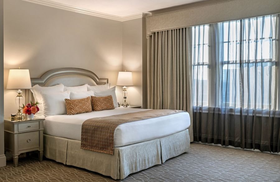 King bed with a patterned throw by bedside lamps under a valence in Classic King at Warwick Melrose Dallas
