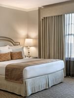 King bed with a patterned throw by bedside lamps under a valence in Classic King Accessible at Warwick Melrose Dallas