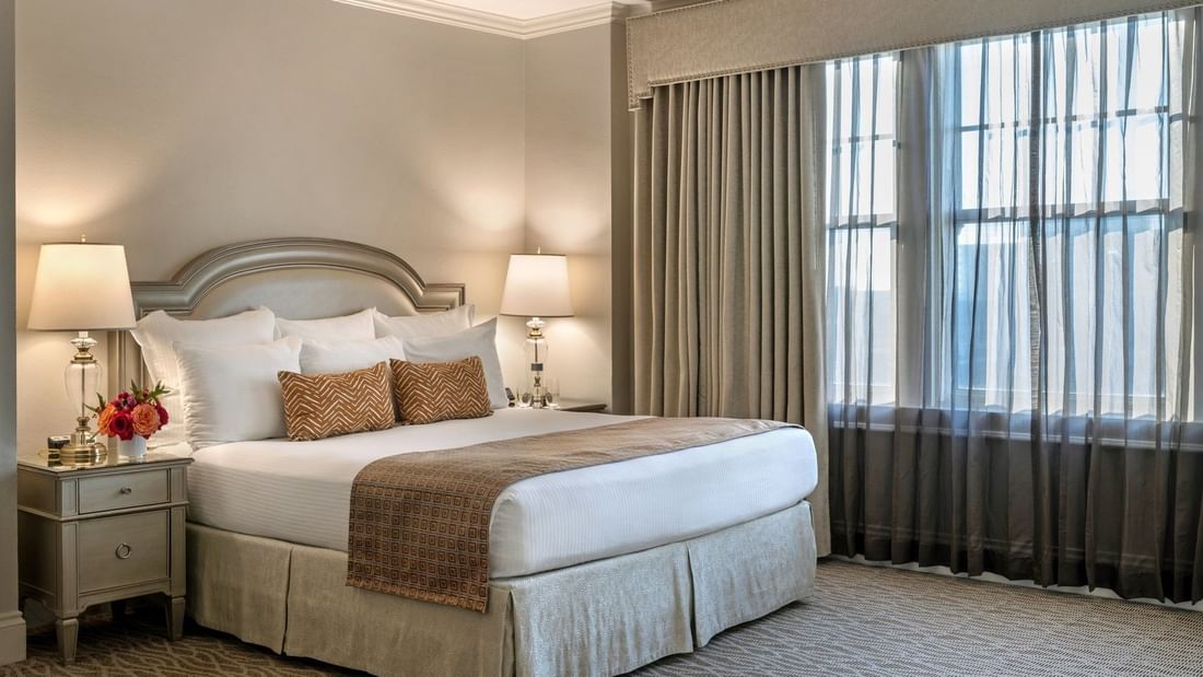 King bed with a patterned throw by bedside lamps under a valence in Classic King at Warwick Melrose Dallas