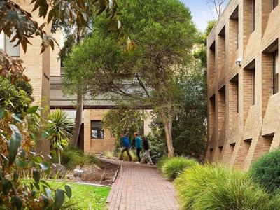 Two people walking down a brick pathway at La Trobe University Chisholm College.
