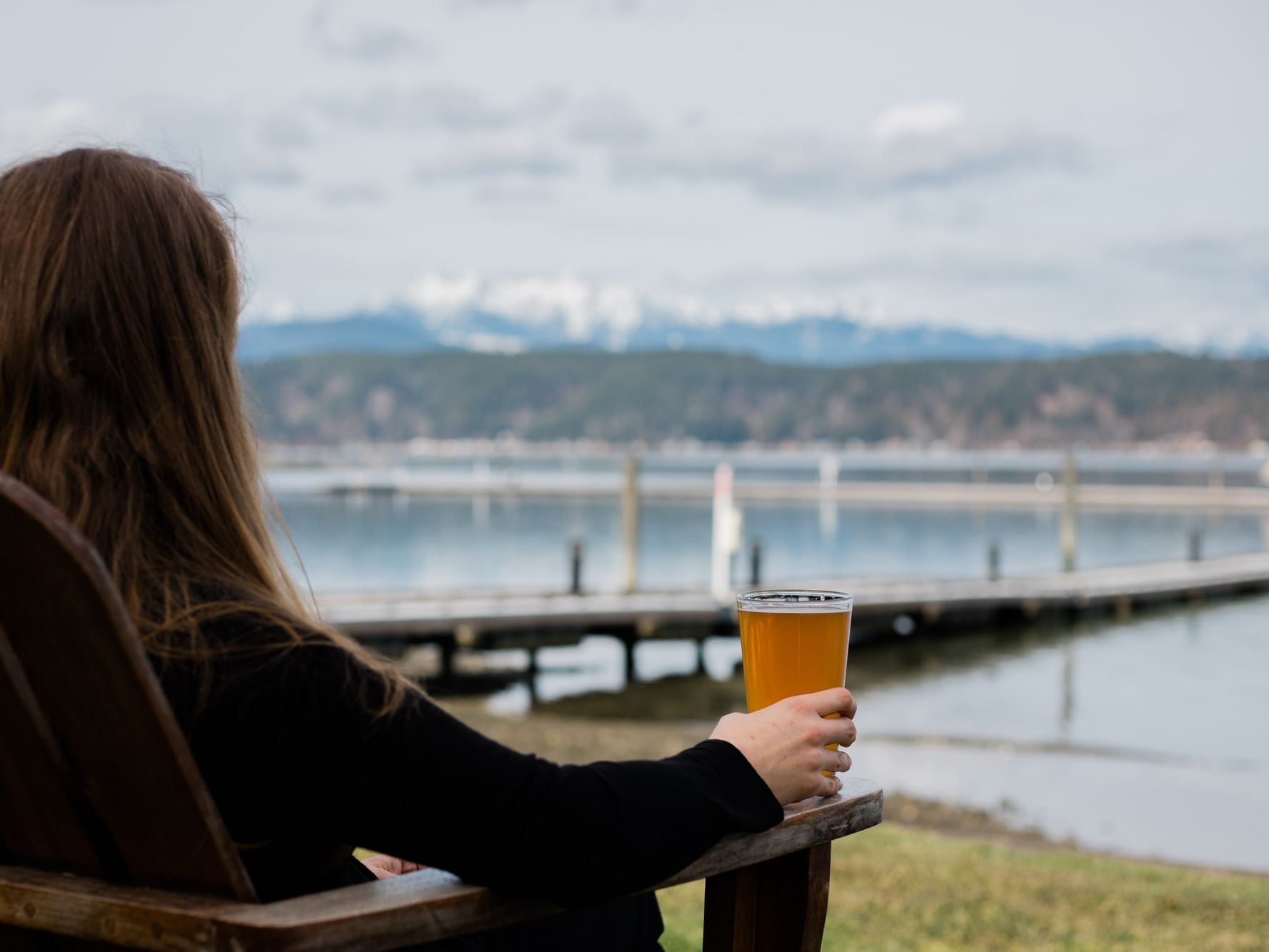 A lady watching the lake while holding a beer at Alderbrook Resort & Spa