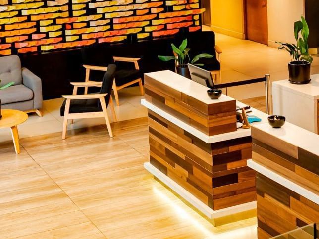 El moderno vestíbulo del hotel HCC Costanera Concepción cuenta con mostradores de recepción de madera y una acogedora zona de descanso.
