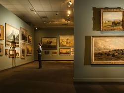 A man looking at the paintings in The Glenbow Museum near Carriage House Hotel