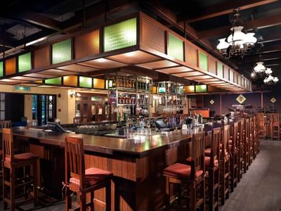 RP and Whisky Bar at The Saujana Hotel Kuala Lumpur with wooden stools, a backlit bar, and chandeliers