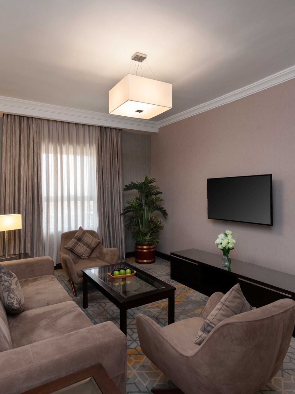 TV lounge area with plush seating and carpeted floors in Executive One-Bedroom Suite at Warwick Hotel Jeddah