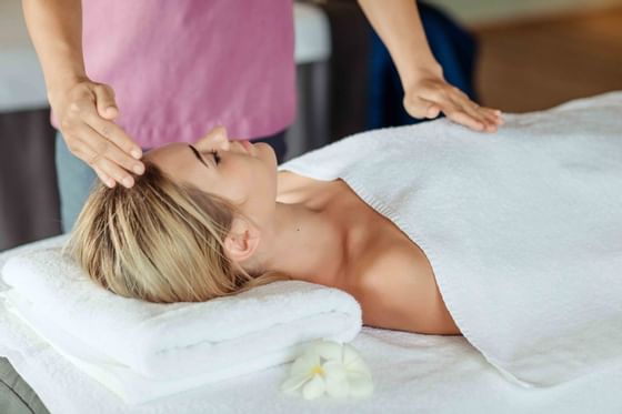 A lady relaxing on the treatment bed at Amatara Wellness Resort