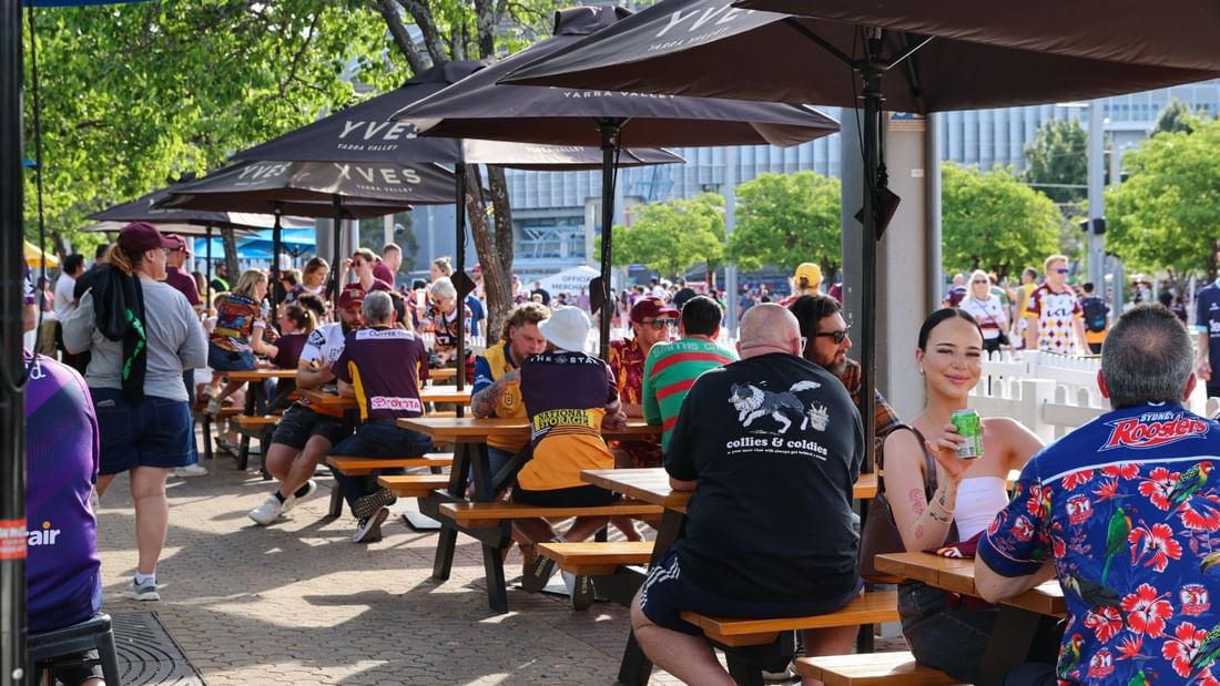 Patrons enjoying drinks at outdoor picnic tables under umbrellas at The Brewery Bar + Kitchen Novotel Sydney Olympi