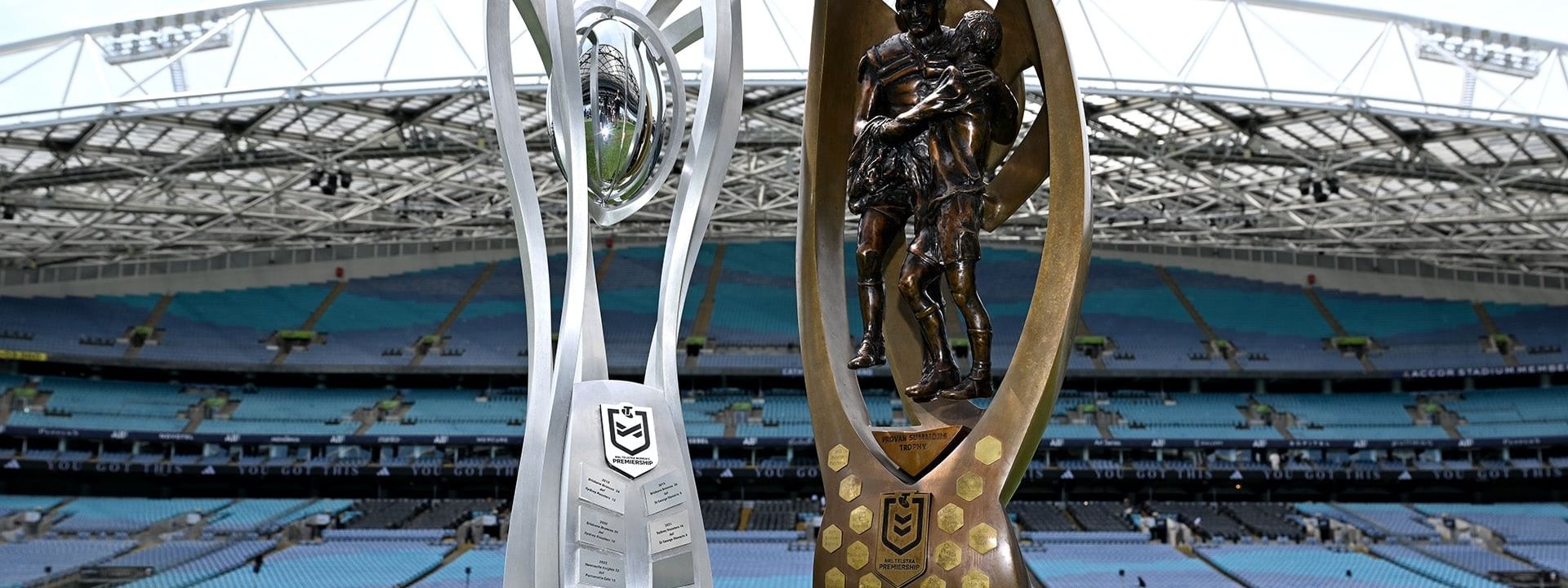 NRL and NRLW Grand Final 2026 trophies displayed on a stadium field.
