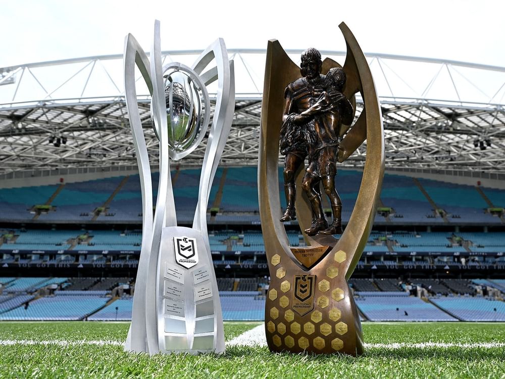 NRL and NRLW Grand Final 2026 trophies on the field in front of an empty stadium.