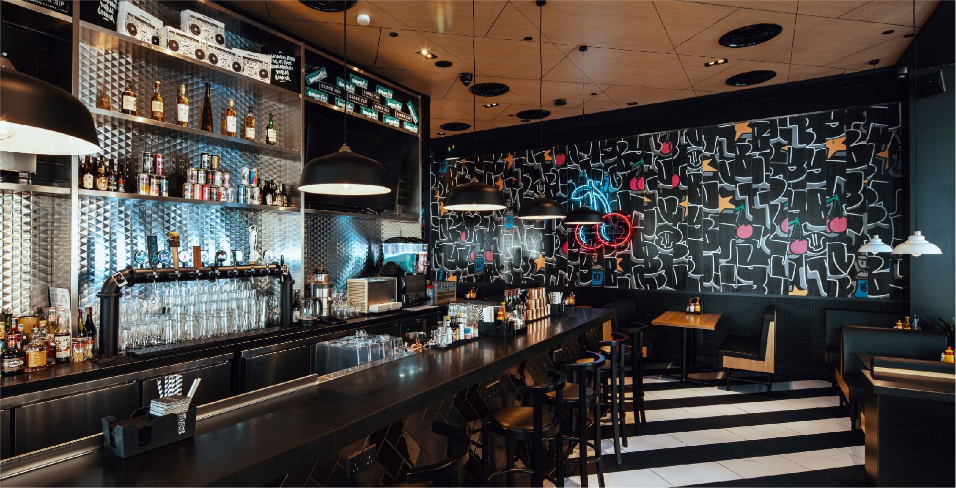 The stylish bar area at Black Tap, Sunway Resort, featuring a graffiti wall and varied seating