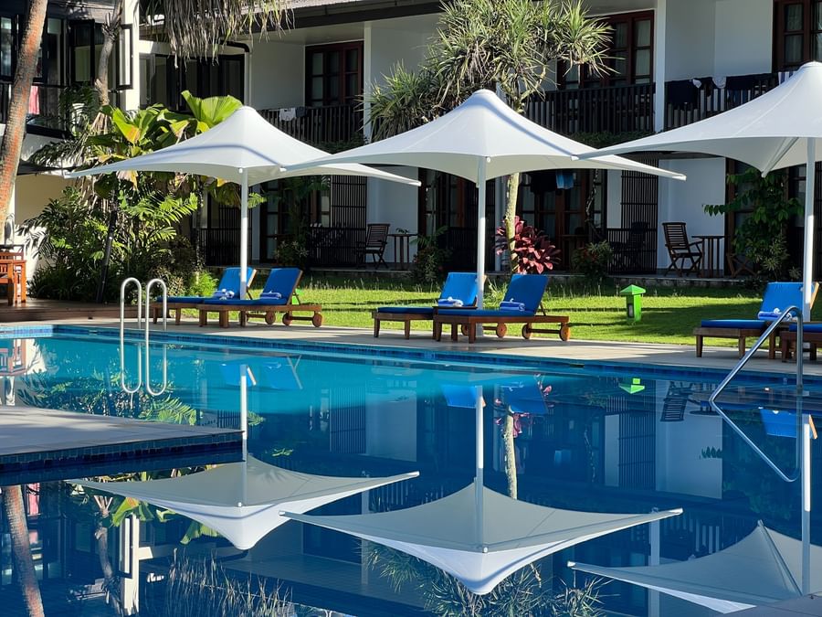 Blue loungers and white umbrellas by a pool at Warwick Fiji Resort and Spa.
