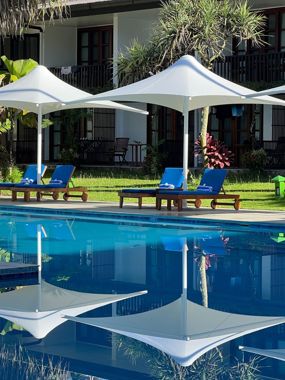 Blue pool with lounge chairs under white umbrellas at Warwick Fiji Resort and Spa in Korolevu.