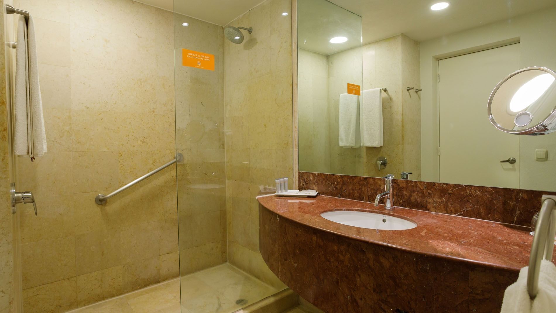 2 Double Deluxe bathroom with a reddish marble vanity, glass shower partition, and white towels at Real Inn Torreon