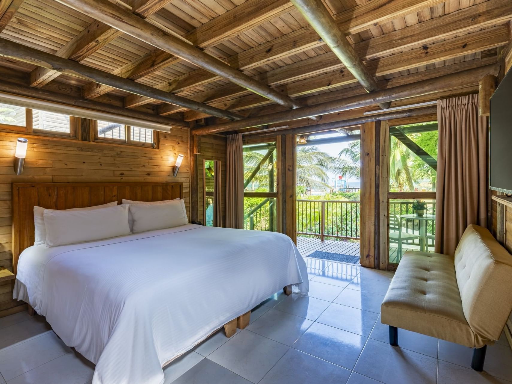 Comfy bed and couch with balcony area in Bungalow room at Hotel Isla Del Encanto