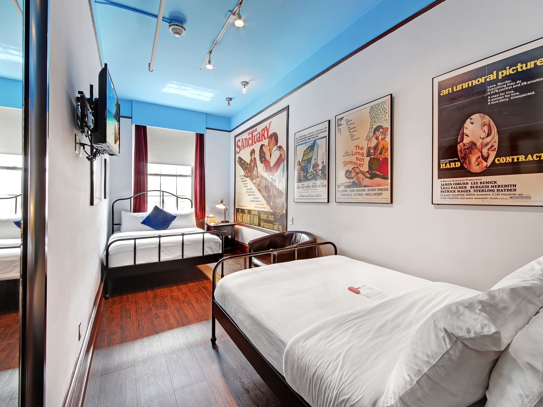 Interior of a Quadruple Room with three beds and vintage posters at Chelsea Pines Inn in New York.