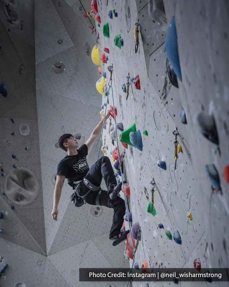 enthusiastic climber scaling a vibrant indoor rock climbing wall - Lexis MY