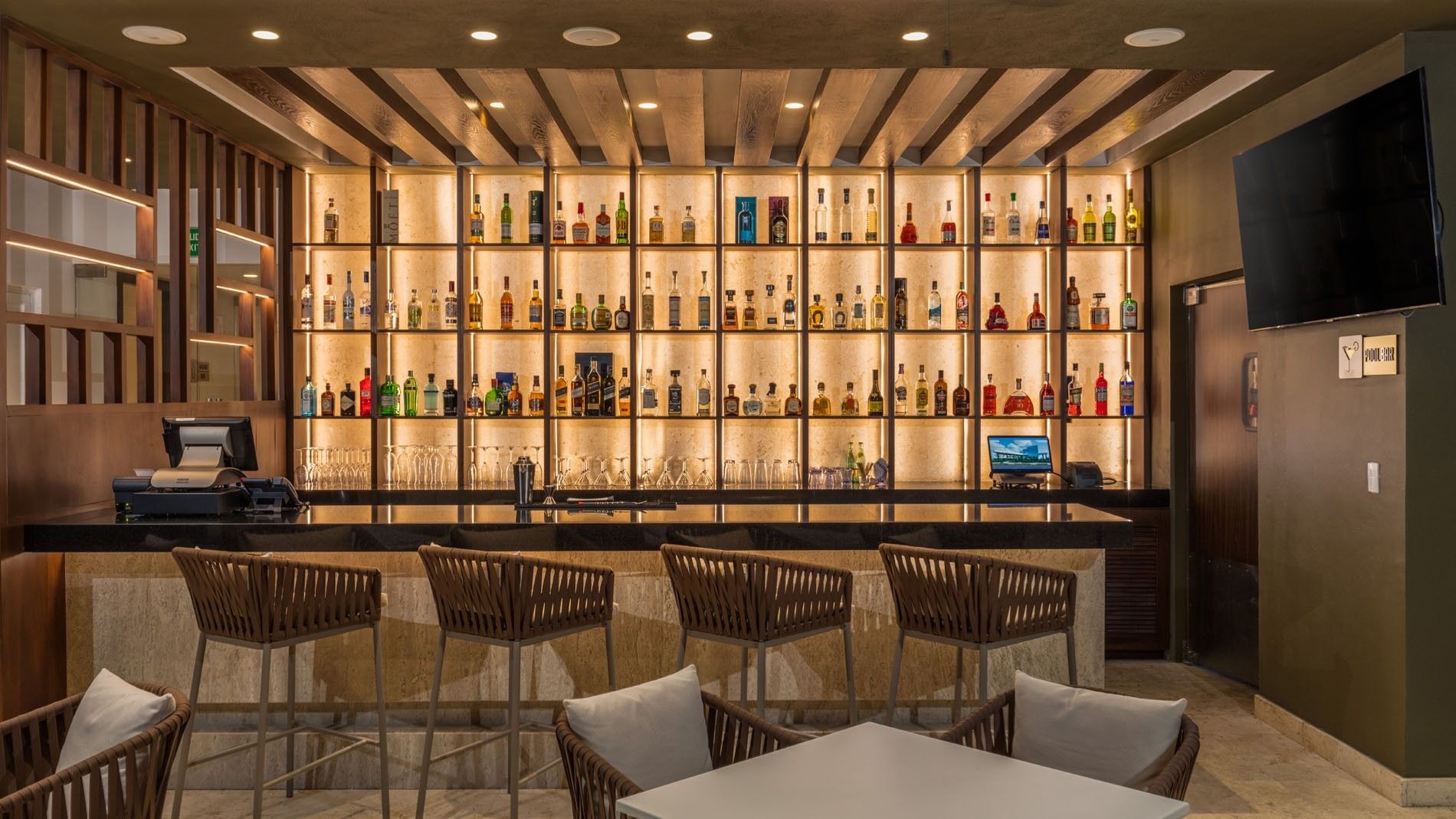 Expansive illuminated spirits display in Blue Bar bar with modern stools and warm lighting at Camino Real Merida