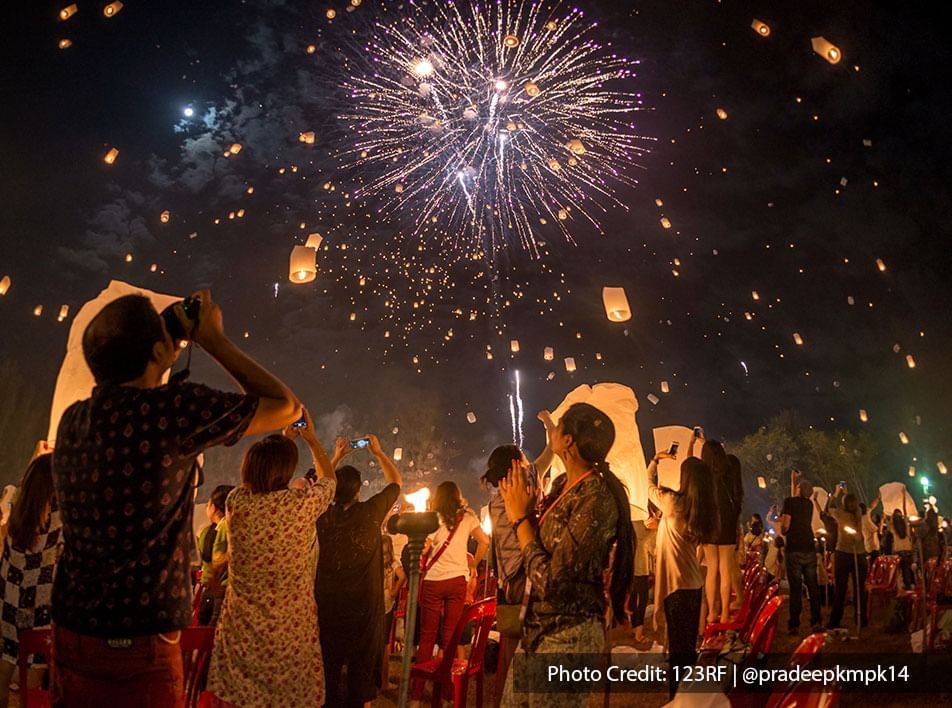 crowd watching fireworks and lanterns at night