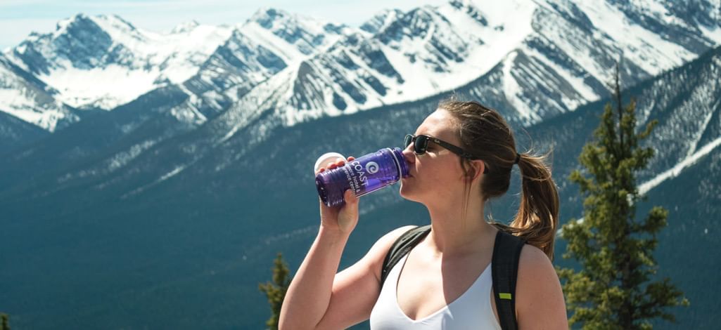 girl drinking water from a coast hotel bottle