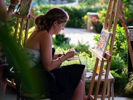 Woman painting outdoors among greenery and flowers at Golden Rock Resort