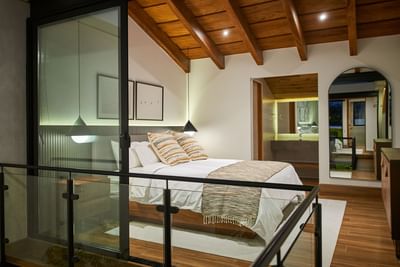 Casa Cielo bedroom with wooden beams, glass wall, cozy lighting, and neutral accents at Singular Signature Residences