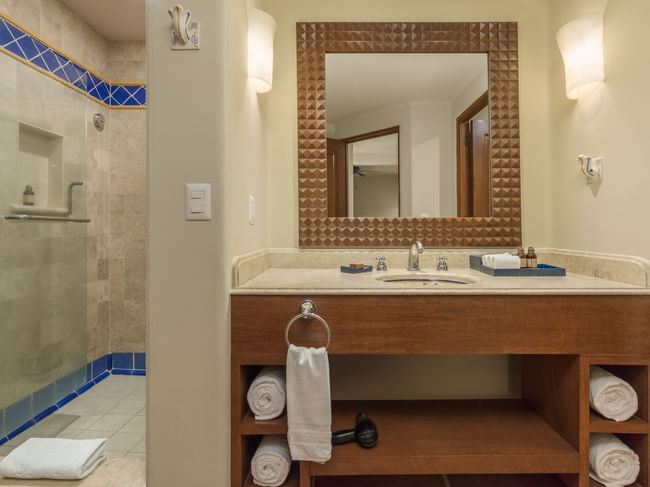 Bathroom with wood-framed mirror vanity and glass shower in the Studio 2 Queen Beds at Hacienda Del Mar Los Cabos.
