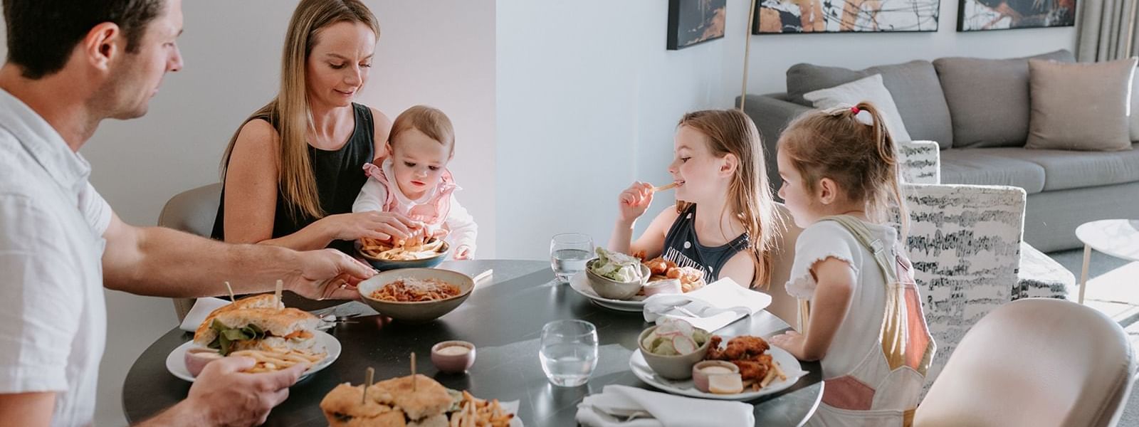 Family enjoying there meals on a dining table by a lounge at Pullman Quay Grand Sydney