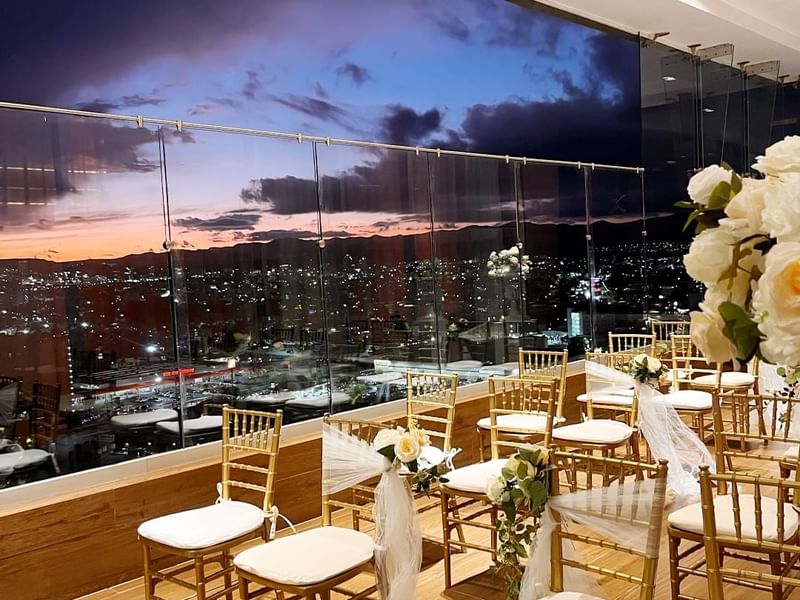 Elegant wedding setup with gold chairs, overlooking a city skyline in Tangamanga Terrace at Fiesta Americana San Luis Potosi