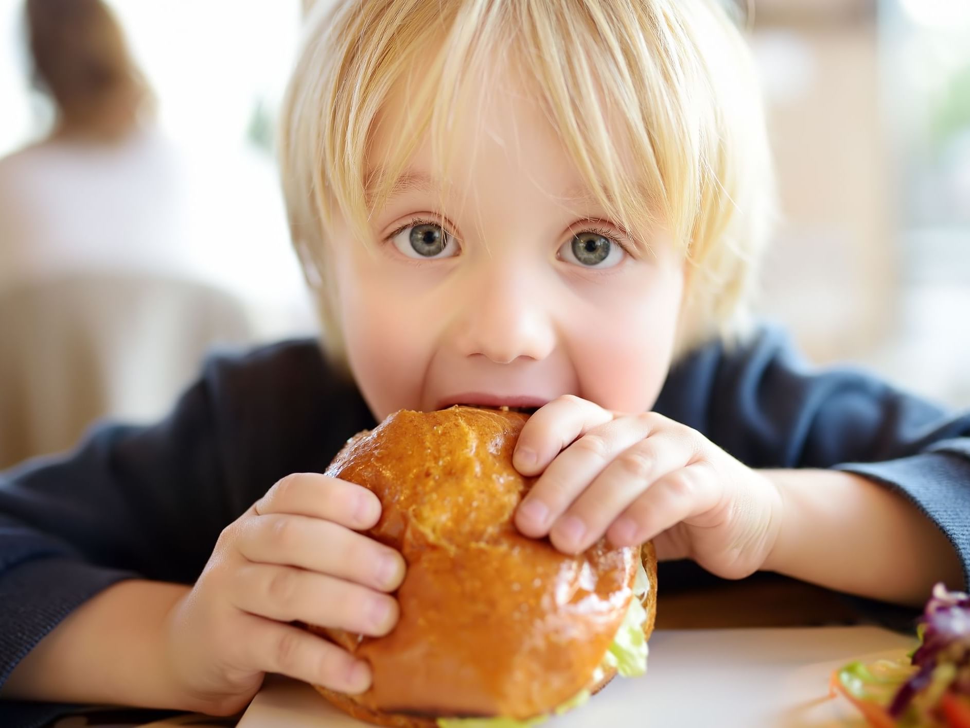 Child enjoying a burger served for Free Kids Breakfast at Hotel Grand Chancellor Brisbane