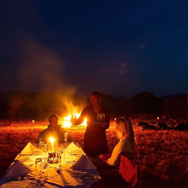 Travelers enjoying a campfire dinner at Kirawira Serena Camp