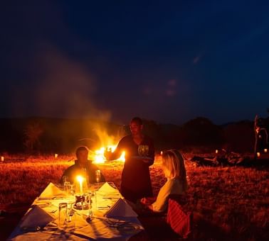 Travelers enjoying a campfire dinner at Kirawira Serena Camp