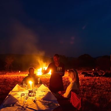 Travelers enjoying a campfire dinner at Kirawira Serena Camp