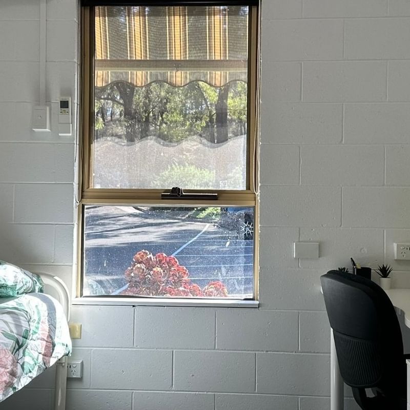 A cozy room with a bed, desk, chair, and window at La Trobe University - Orde House.