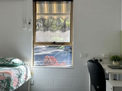 A cozy room with a bed, desk, chair, and window at La Trobe University - Orde House.