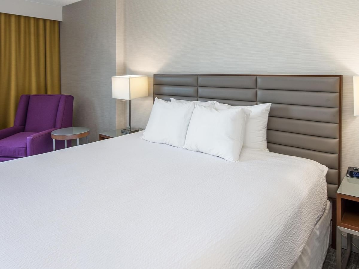 Coast King room with king bed, gray headboard, purple armchair, and bedside lamps at Coast Prince George Hotel