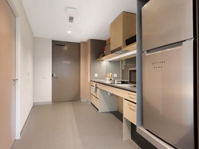 Modern kitchen with refrigerator, sink, and counter in La Trobe University apartments.