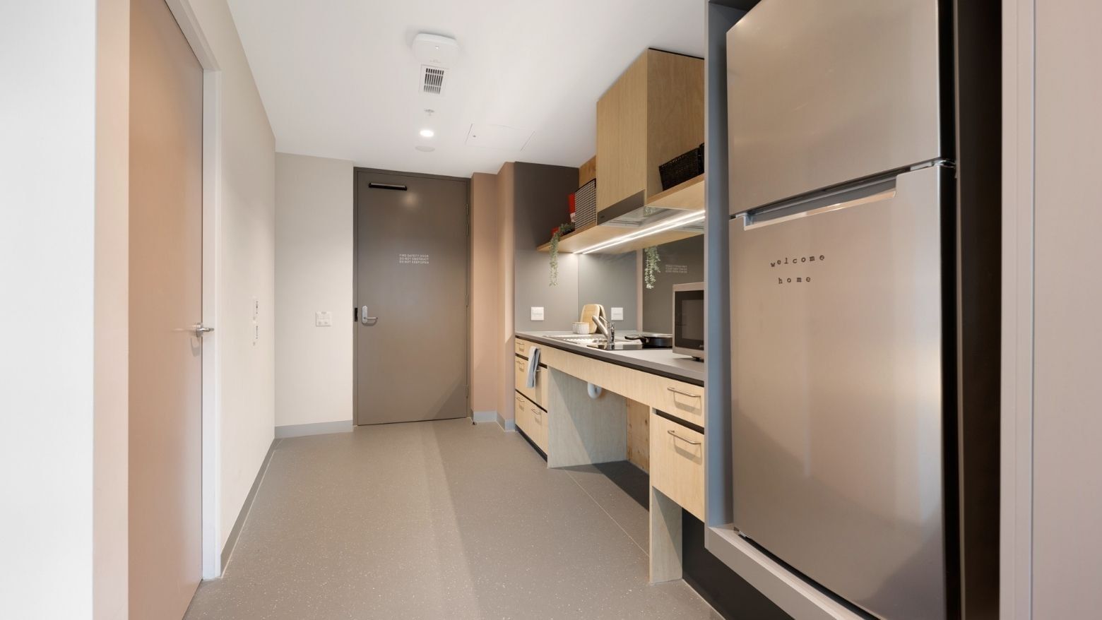 Modern kitchen with refrigerator, sink, and counter in La Trobe University apartments.