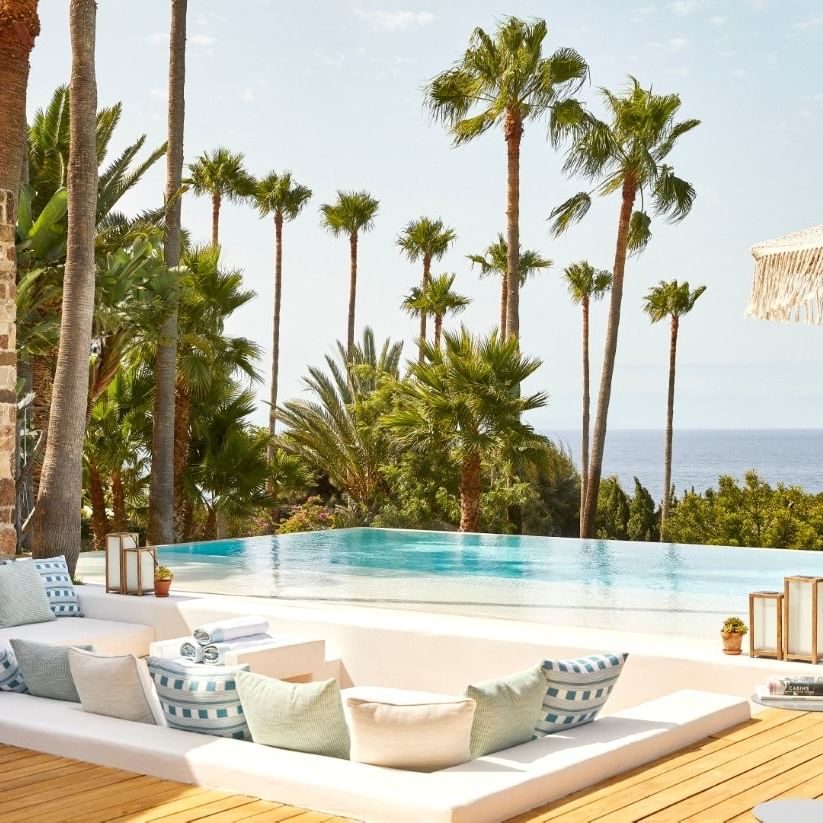 Outdoor lounging area with pool and ocean view at Villa Punta Paloma, Marbella Club in Marbella.