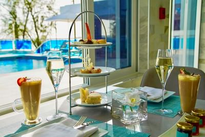 Three-tier afternoon tea stand with sandwiches and treats by the pool at The Abidah Hotel by Accra