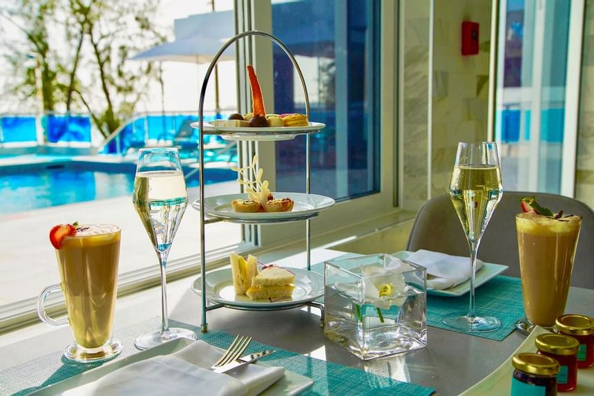 Three-tier afternoon tea stand with sandwiches and treats by the pool at The Abidah Hotel by Accra