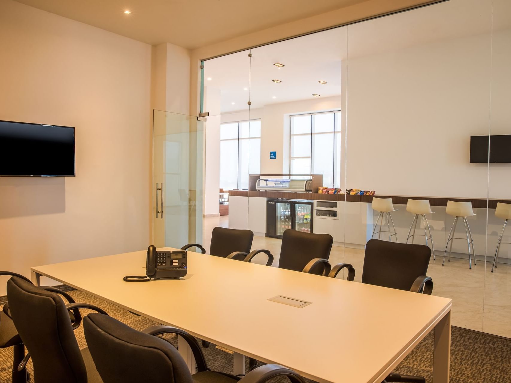 Mesa de conferencias y televisor de pared en una sala de reuniones de One Hotels