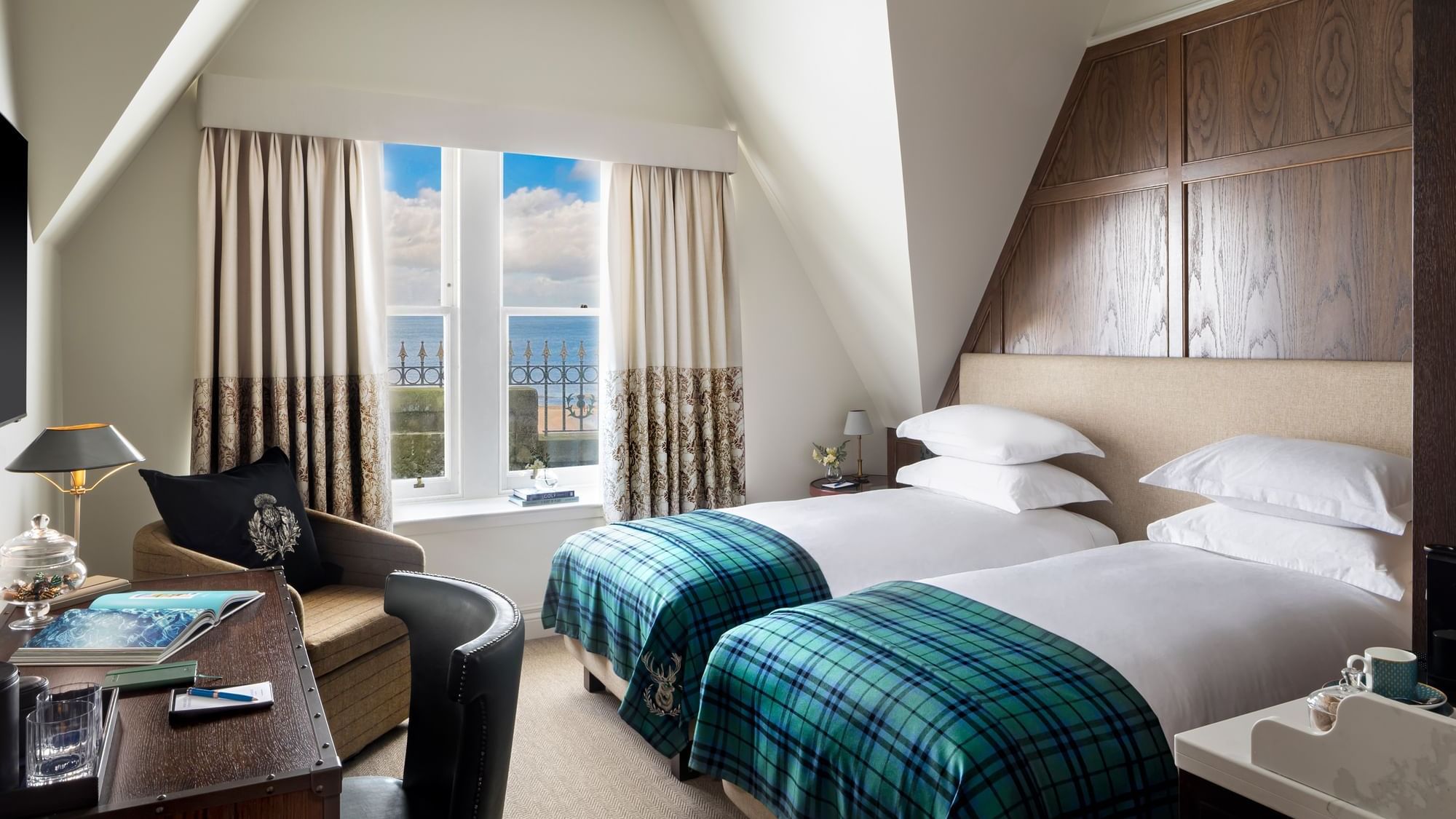 Work desk facing two beds by the window with ocean view in Deluxe twin with sea view at Seaton House