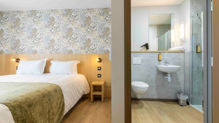 A bedroom with bed and adjacent bathroom at The Originals City Hotel du Parc Gravelines.