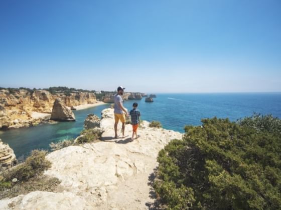 Father and son enjoy a hike on a cliffside in Portugal