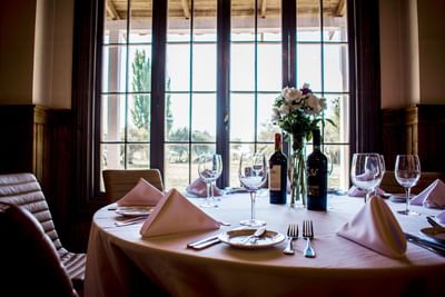 Dining table with wine & flowers by leather chairs under a wooden ceiling in a event room at NOI Blend Colchagua